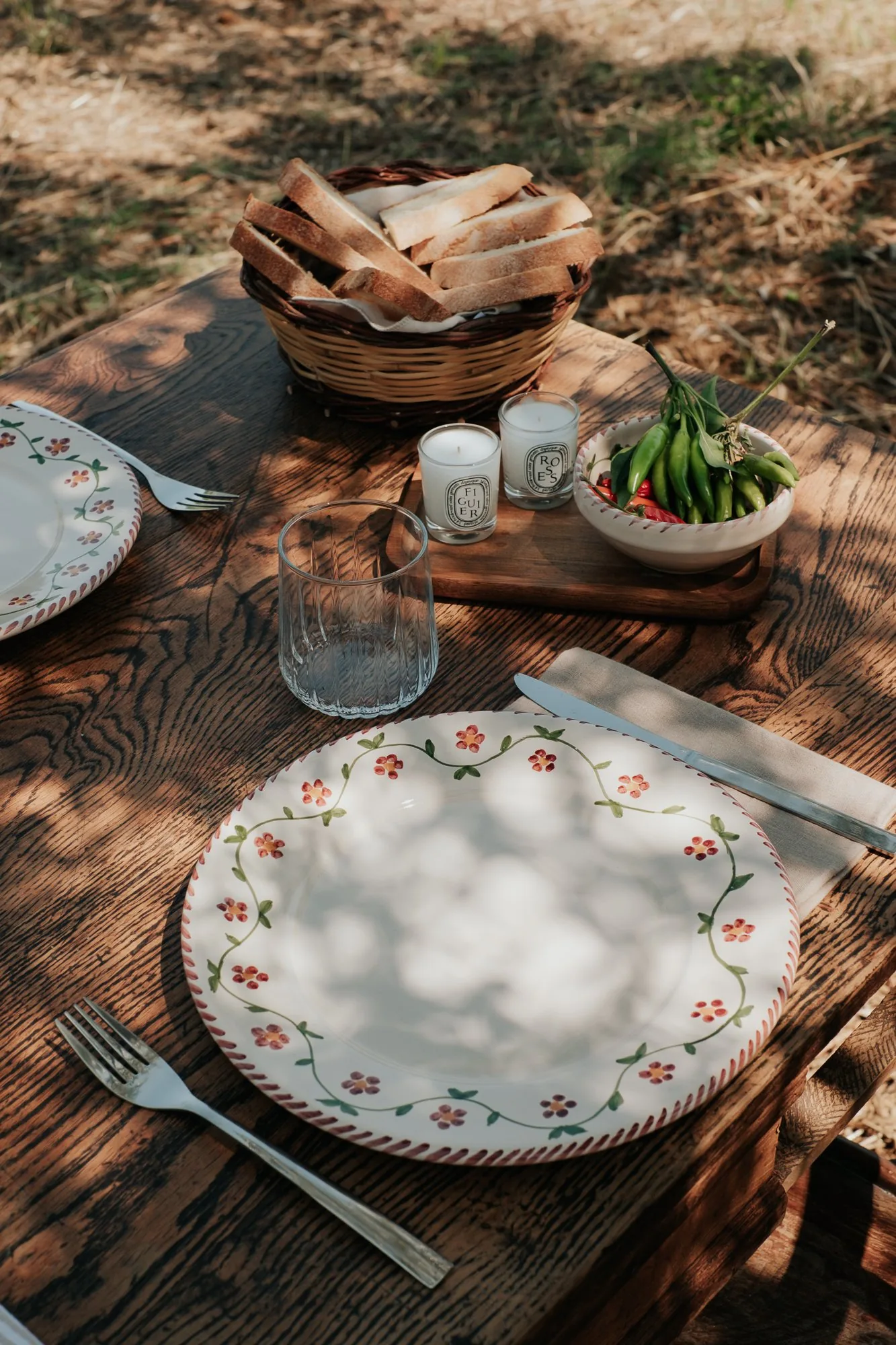 Couvert dressé sur une table en bois au jardin, avec une corbeille de pain
