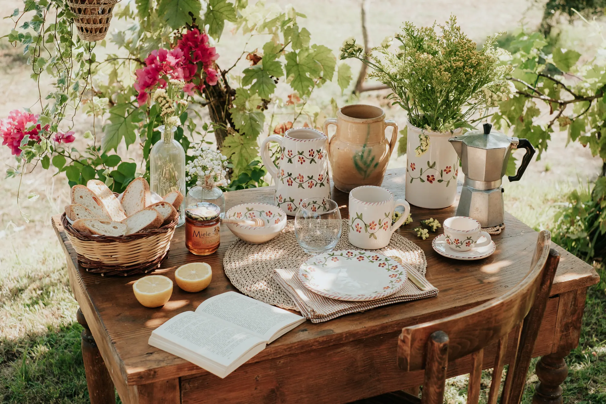 Petit-déjeuner dressé sous la vigne avec cafetière italienne, carafe et bouquets
