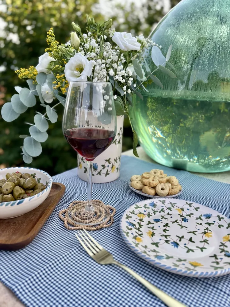 Verre de vin et assiette Fiori di Campo sur une nappe bleue