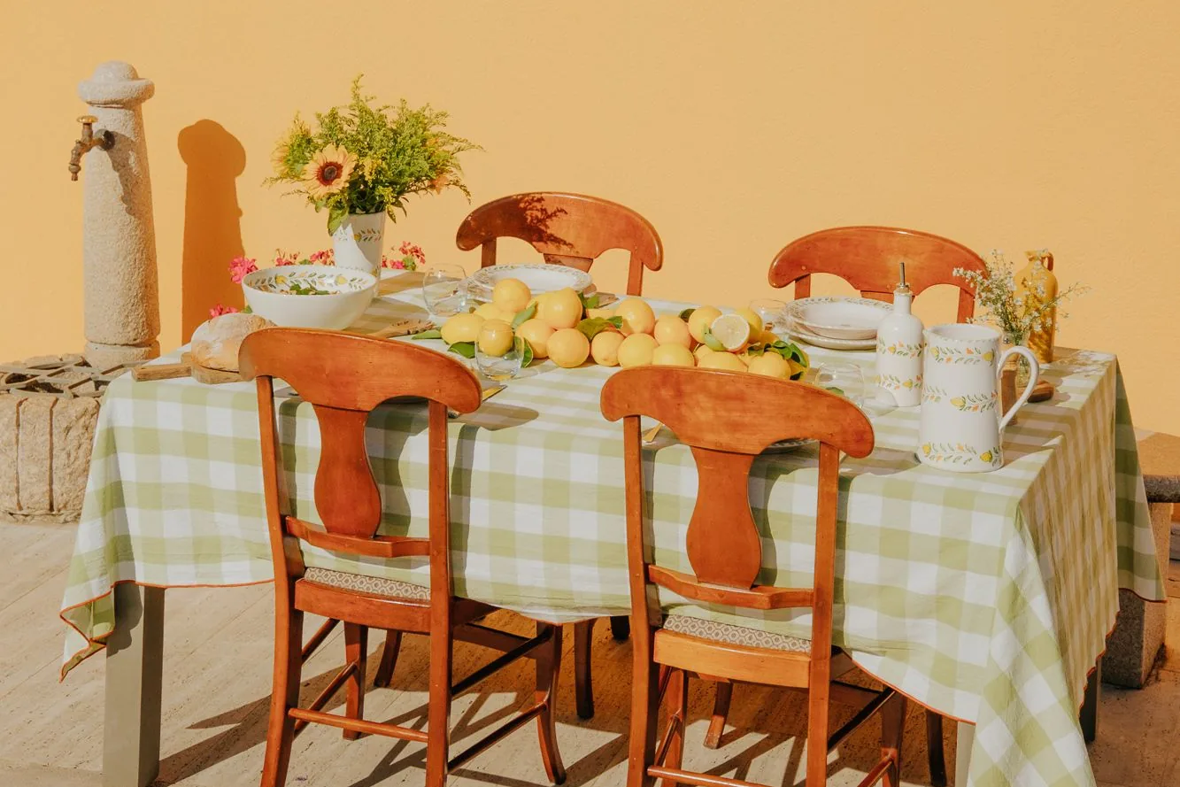 Table dressée au soleil avec la vaisselle Sapore di Limone, des citrons et une nappe vichy verte