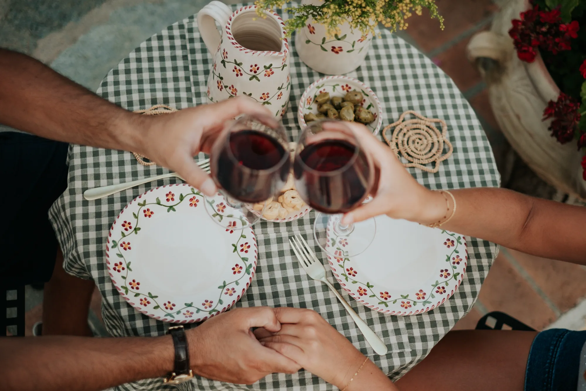 Deux verres de vin rouge trinquent au-dessus d’assiettes Profumo di Primavera
