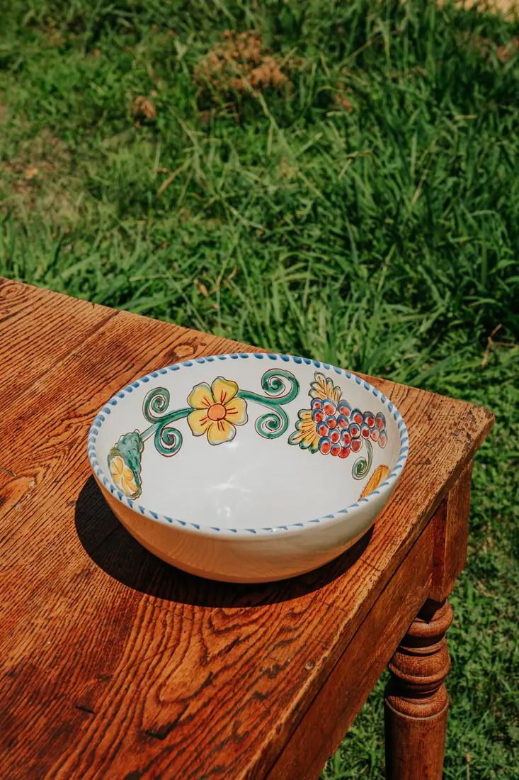 Saladier Frutta del Sud posé sur une table en bois, devant l'herbe