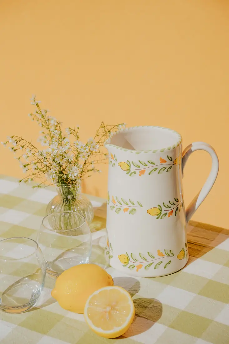 Carafe Sapore di Limone devant un mur ocre, avec des citrons coupés