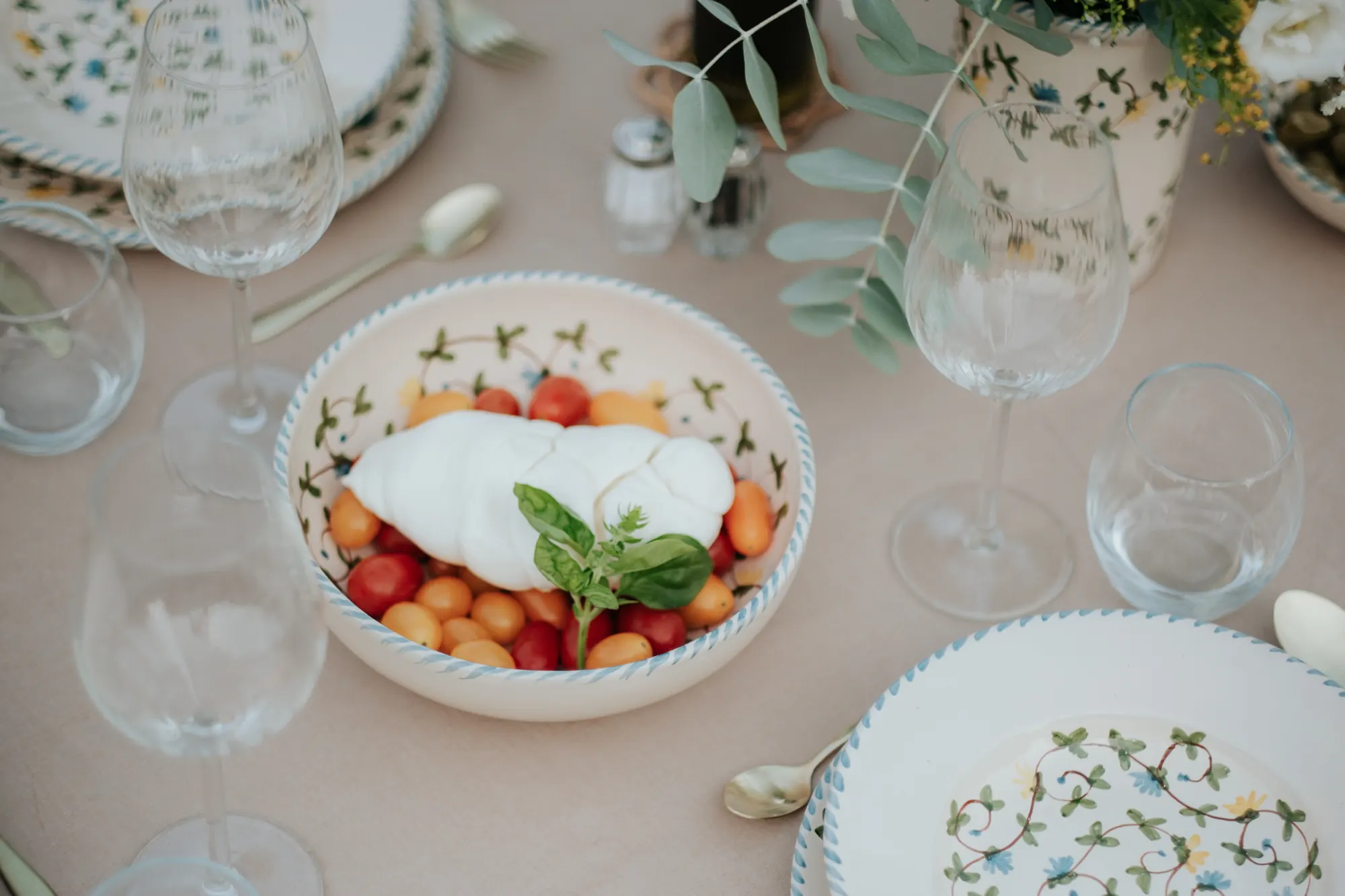 Table dressée avec la vaisselle Fiori di Campo et une salade de tomates